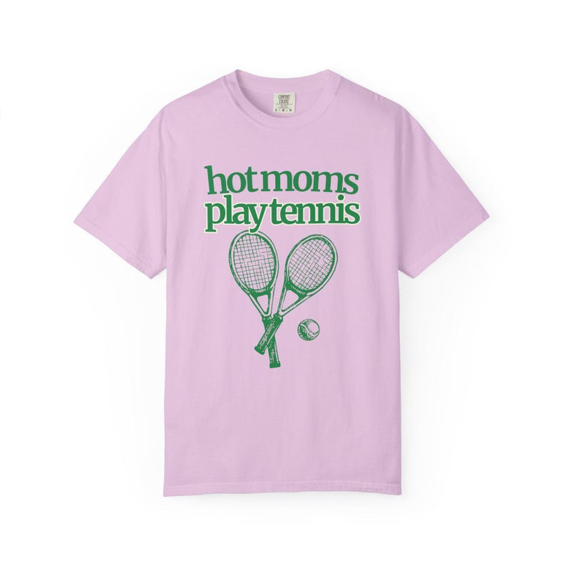 model is wearing comfort colors short sleeve shirt in flo blue with hot moms play tennis graphic in pink on front