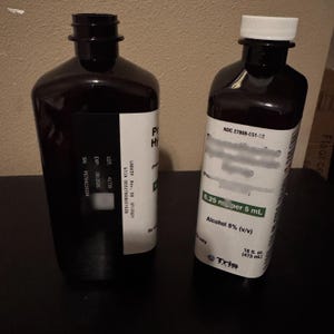 May include: Two dark amber plastic bottles with white labels. The left bottle is open with a black threaded neck. The right bottle has a white screw cap and a label displaying NDC 27808-051-02, 6.25 mg per 5 mL, Alcohol 8% (v/v), and 16 fl. oz. (473 mL).