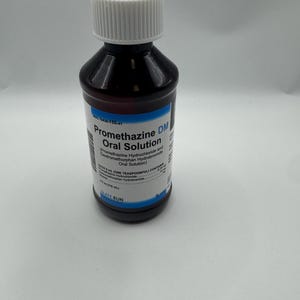 May include: A dark amber plastic bottle of Promethazine DM Oral Solution with a white ribbed screw cap. The label features blue accents and white text, including the volume 4 fl oz (118 mL) and the manufacturer name Slate Run Pharmaceuticals.