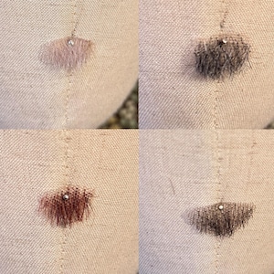 May include: A composite image showing four swatches of textured, fibrous material in light beige, dark gray, reddish-brown, and dark brown, each pinned to a light-colored, woven fabric surface with a small, round, silver-toned metal pin.