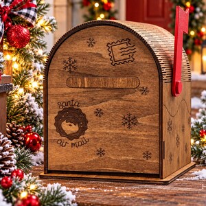 Peut inclure: Une boîte aux lettres en bois avec un dessus incurvé et un drapeau rouge sur le côté. L'avant présente une fente horizontale, des flocons de neige gravés, un motif de timbre et un sceau circulaire avec un visage et le texte Santa air mail.
