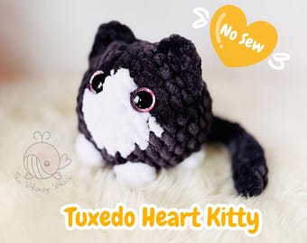 May include: A black and white crocheted plush toy cat with a heart-shaped head and a long tail. The cat is wearing a tuxedo-style outfit. The text "No Sew" is written on a yellow heart in the background.
