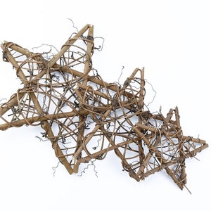 May include: Three woven star ornaments made of brown twigs. The stars are layered on top of each other, with the largest star in the back and the smallest star in the front.