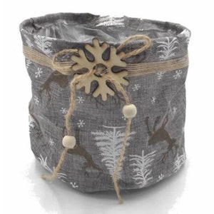 May include: A gray fabric storage basket with a snowflake design and a wooden snowflake accent. The basket has a drawstring closure and is decorated with white trees and reindeer.