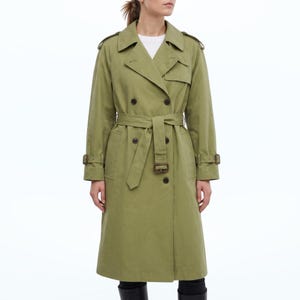 Könnte beinhalten: Ein olivgrüner Trenchcoat mit doppelter Knopfleiste, breitem Reverskragen, Schulterklappen und einem passenden Stoffgürtel mit rechteckiger Schnalle. Der Mantel hat lange Ärmel mit verstellbaren Riegeln an den Manschetten und zwei Seitentaschen.