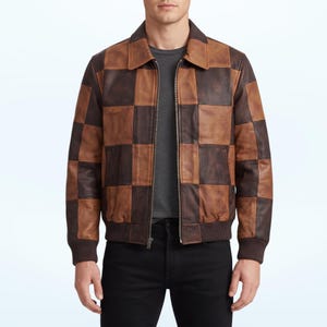 Puede incluir: Una chaqueta tipo bomber de cuero con un patrón de cuadros que alterna cuadrados de cuero marrón oscuro y marrón claro. La prenda cuenta con un cuello clásico, una cremallera metálica frontal completa y puños y dobladillo de punto acanalado.