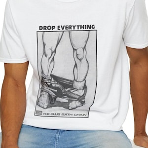 Puede incluir: Camiseta blanca con una ilustración en blanco y negro de las piernas de una persona con el texto "DROP EVERYTHING" y "THE CLUB BATH CHAIN" impreso en la parte delantera.