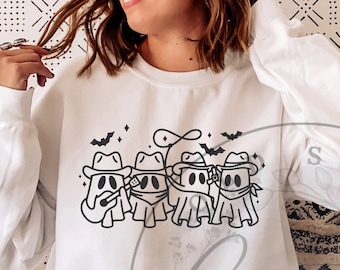 Puede incluir: Sudadera blanca de cuello redondo con un gráfico en blanco y negro de cuatro figuras de fantasmas con sombreros de vaquero y pañuelos. El diseño también incluye murciélagos y un lazo. Un diseño divertido y espeluznante para Halloween.