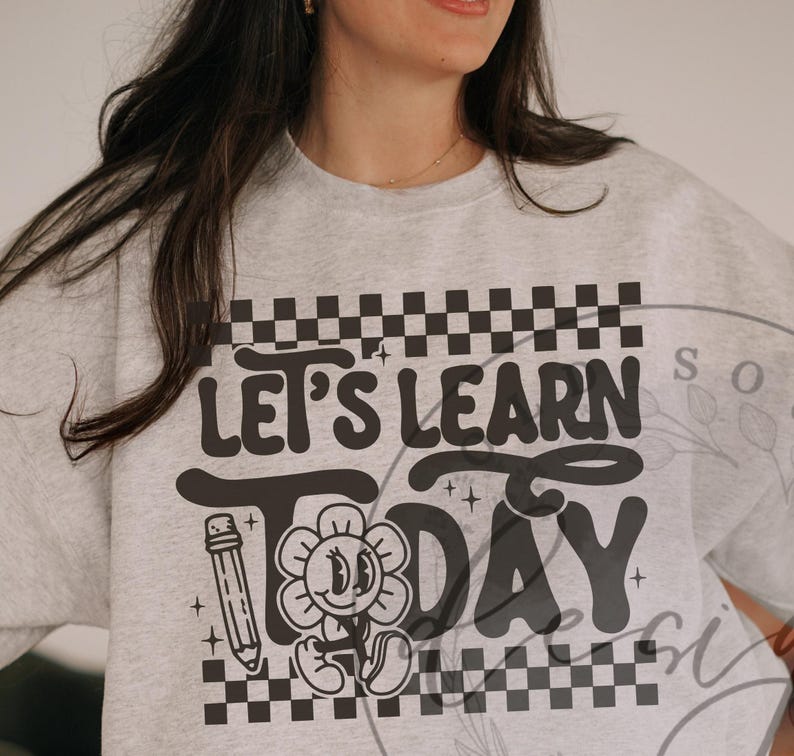 May include: A light gray sweatshirt with the words "LET'S LEARN TODAY" in a black, retro font. The design includes a pencil and a smiling flower. The top has a checkered pattern.