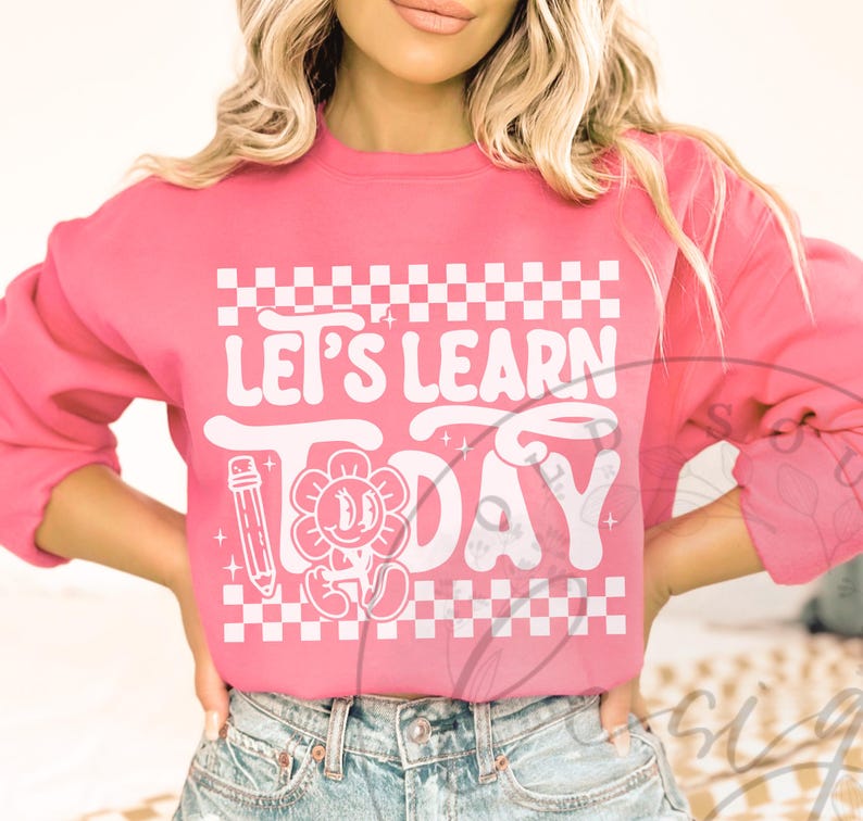 May include: Pink sweatshirt with the text "LET'S LEARN TODAY" in white, featuring a flower with a smiling face and a pencil graphic. The design includes a white and pink checkered pattern.