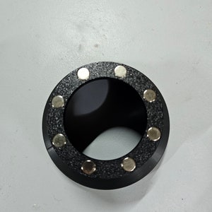 Könnte beinhalten: Schwarzer Kunststoffring mit acht silbernen Magnetverschlüssen.