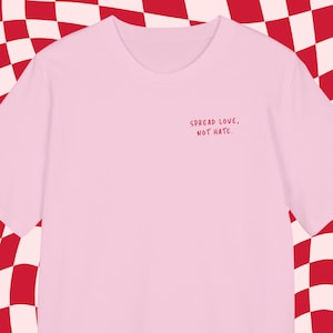 Könnte beinhalten: Pinkes T-Shirt mit dem Text "SPREAD LOVE, NOT HATE." in rot gestickt.