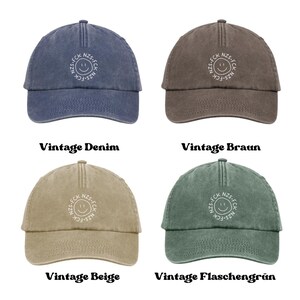 May include: Four baseball caps in vintage denim blue, brown, beige, and bottle green. Each cap features a centered white embroidered circular design with a smiley face and the text FCK NZS repeated around the perimeter of the circle.