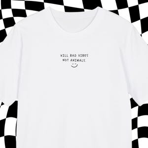 Op de afbeelding: Wit t-shirt met de zwarte tekst "KILL BAD VIBES NOT ANIMALS" en een smiley. Deze casual top is gemaakt van een zachte stof, perfect voor dagelijks gebruik.