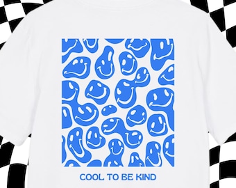 May include: White t-shirt featuring a blue smiley face pattern. The design includes various shapes of smiling faces. The text "COOL TO BE KIND" is printed in blue below the pattern. The shirt has short sleeves and a crew neck.