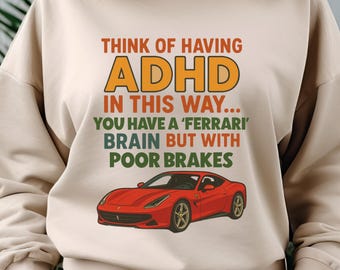 May include: Beige sweatshirt featuring the text "THINK OF HAVING ADHD IN THIS WAY... YOU HAVE A 'FERRARI' BRAIN BUT WITH POOR BRAKES" and a red sports car graphic. The text is in orange, green, and white.