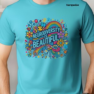 May include: A turquoise t-shirt with a colorful graphic design featuring flowers, a rainbow, and the text "Neurodiversity is Beautiful".