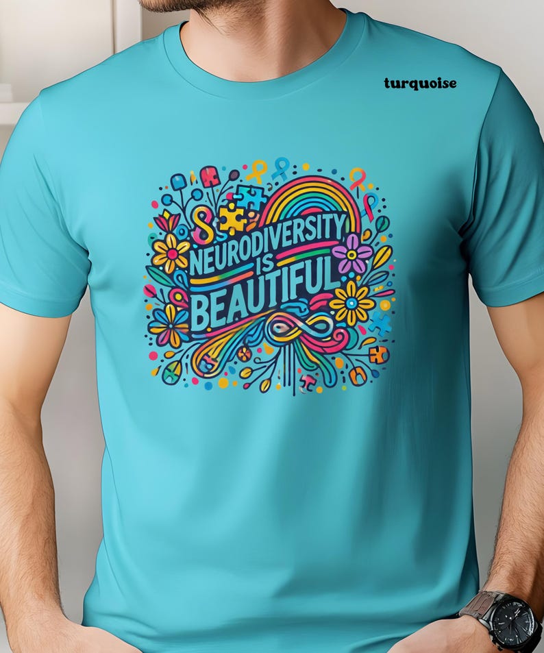May include: A turquoise t-shirt with a colorful graphic design featuring flowers, a rainbow, and the text "Neurodiversity is Beautiful".