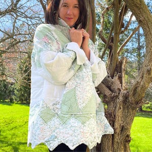 May include: A quilted jacket with a patchwork design. The jacket features a mix of white, green gingham, and floral patterns. It has a high collar and a scalloped hemline, offering a cozy and unique style.