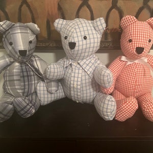 May include: Three handmade teddy bears in a row. The bears are made from patterned fabric. One is gray plaid, one is blue and white plaid, and the third is red and white gingham. Each bear has a button nose and a stitched mouth.