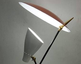 May include: A mid-century modern style desk lamp with a white cone-shaped shade and a larger, brown, leaf-shaped shade. The lamp has a black metal frame with brass accents and a black base.