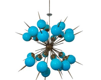 May include: A modern chandelier with a starburst design featuring multiple blue glass globes on gold metal arms.
