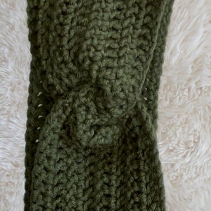 May include: A green crocheted headband with a twisted knot design.