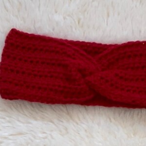 May include: A red crocheted headband with a twisted design.