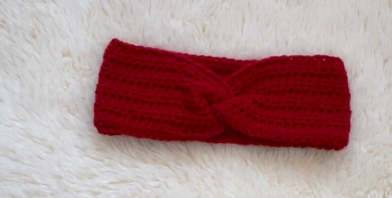 May include: A red crocheted headband with a twisted design.