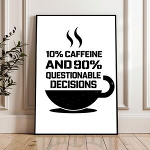 Könnte beinhalten: Schwarz gerahmter Druck mit dem Text "10% Caffeine and 90% Questionable Decisions" über einer schwarzen Kaffeetassengrafik. Der Druck wird an einer weißen Wand mit Holzboden angezeigt.