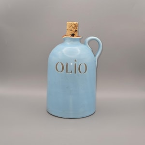 May include: A light blue ceramic oil cruet with a handle and a cork stopper. The word "OLIO" is embossed on the front. The cruet is approximately 7 inches tall.