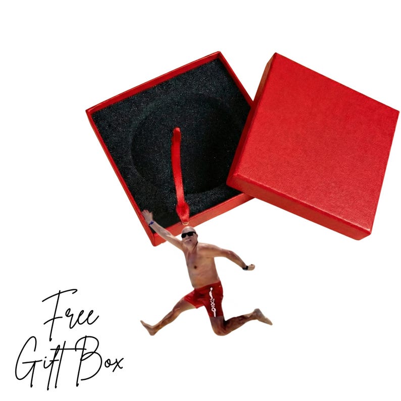 A man in red shorts is jumping out of a red gift box, with the box open and the man's arms raised.