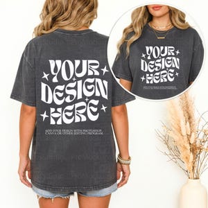 May include: Dark gray t-shirt with the text "YOUR DESIGN HERE" in a white, retro font. The shirt also includes the text "ADD YOUR DESIGN WITH PHOTOSHOP, CANVA OR OTHER EDITING PROGRAM". The shirt is worn with denim shorts.