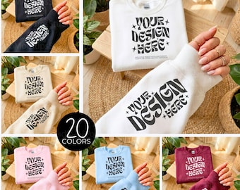 May include: A mockup featuring a variety of crewneck sweatshirts in different colors, including black, white, beige, pink, light blue, and burgundy. Each sweatshirt displays the text "YOUR DESIGN HERE" in a retro font. The image showcases 20 color options.