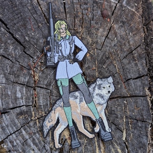 Peut inclure: Écusson brodé représentant un personnage blond en manteau bleu clair, tenant un fusil et debout avec un loup. Le patch présente un design détaillé avec des accents verts et gris, sur un fond texturé.