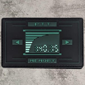 Peut inclure: Patch noir et vert avec le texte "PTT" et "MEMORY" et un graphique d'un écran numérique avec un graphique à barres et des chiffres.
