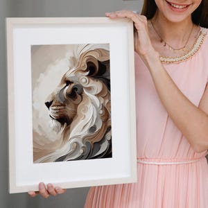 May include: Framed art print featuring a profile of a lion's head. The artwork uses a palette of neutral tones, including beige, brown, and gray, with a focus on the lion's mane. The print is displayed in a white frame.