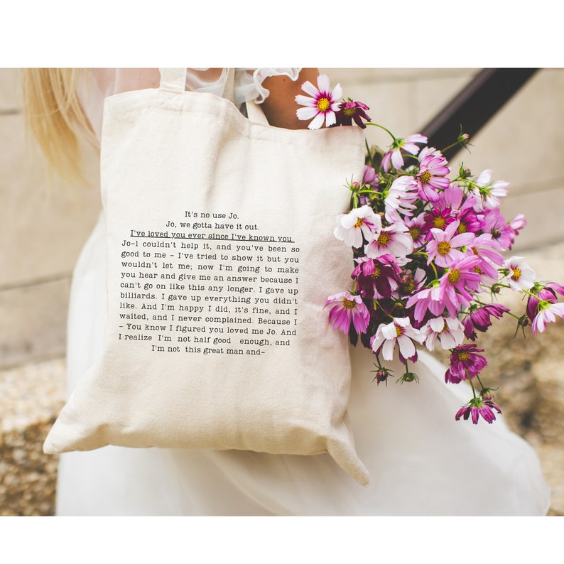 May include: A white tote bag with a black and white text print. The text reads "It's no use Jo. Jo, we gotta have it out. I've loved you ever since I've known you Jo-l couldn't help it, and you've been so good to me - I've tried to show it but you wouldn't let me; now I'm going to make you hear and give me an answer because I can't go on like this any longer. I gave up billiards. I gave up everything you didn't like. And I'm happy I did, it's fine, and I waited, and I never complained. Because I - You know I figured you loved me Jo. And I realize I'm not half good enough, and I'm not this great man and- "