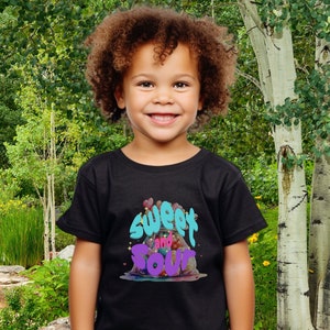 May include: A child wearing a black t-shirt with a colorful graphic that says "Sweet and Sour".