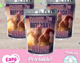 Peut inclure: Trois sachets en aluminium argenté avec un motif imprimé représentant une créature ressemblant à Godzilla et un gorille. Les sachets portent l'inscription "Happy 7th Birthday Byron".