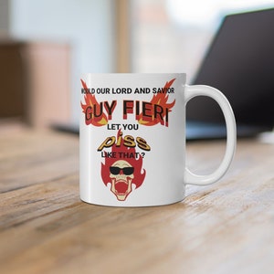 May include: White ceramic mug with the text "WOULD OUR LORD AND SAVIOR GUY FIERI LET YOU PISS LIKE THAT?" in red, yellow, and black. The mug features a cartoon skull with sunglasses and flames.