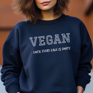 May include: A navy blue sweatshirt with white text that reads "VEGAN UNTIL EVERY CAGE IS EMPTY".