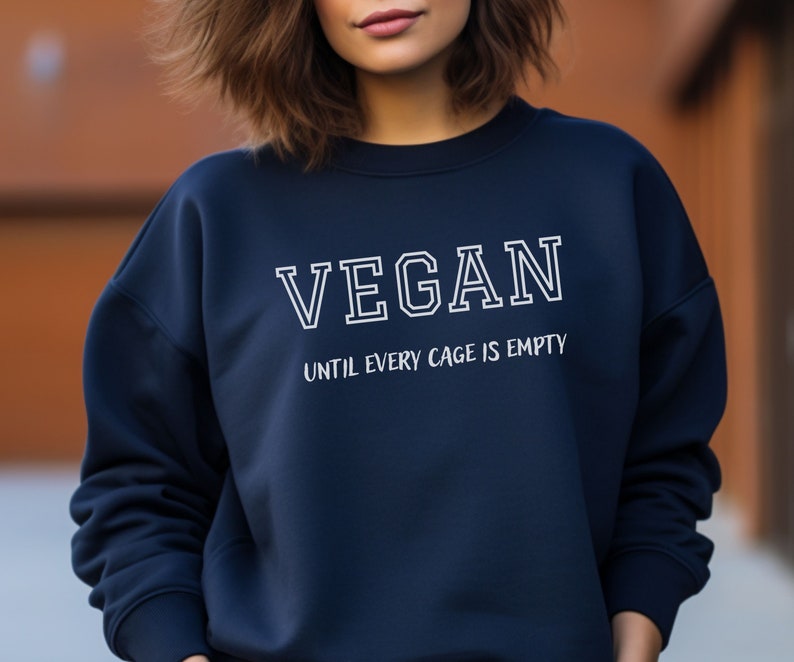 May include: A navy blue sweatshirt with white text that reads "VEGAN UNTIL EVERY CAGE IS EMPTY".