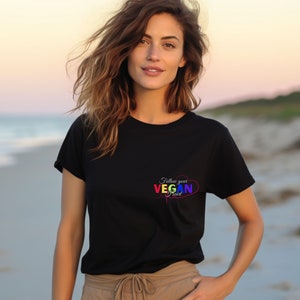Op de afbeelding: Een zwart T-shirt met een regenboog hart en de tekst "Follow your Vegan Heart" op de voorkant.