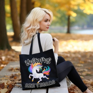 May include: Black tote bag featuring a white unicorn with a rainbow mane and tail. The text on the bag reads "Unicorns are Vegans".