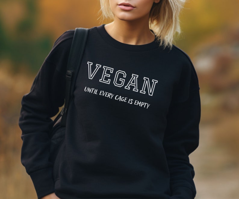 May include: Black sweatshirt with white text that reads "VEGAN UNTIL EVERY CAGE IS EMPTY".