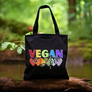 May include: Black tote bag with the text "Vegan is Love" in rainbow colours and rainbow heart shapes.