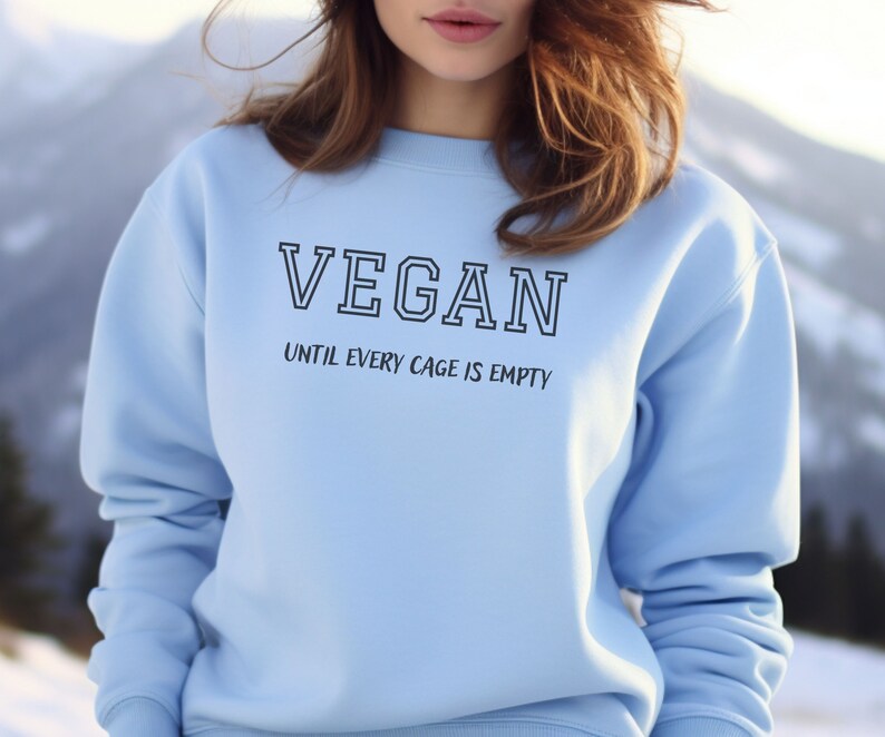 May include: A light blue sweatshirt with the text "VEGAN UNTIL EVERY CAGE IS EMPTY" printed on the front.