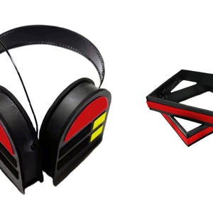 May include: Black noise-cancelling headphones with red and yellow accents. The headphones are folded and have a microphone attached to the left earcup.