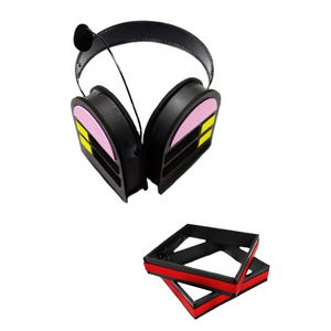 May include: Black noise-cancelling headphones with pink and yellow accents. The headphones are folded and sitting on a black and red storage box.